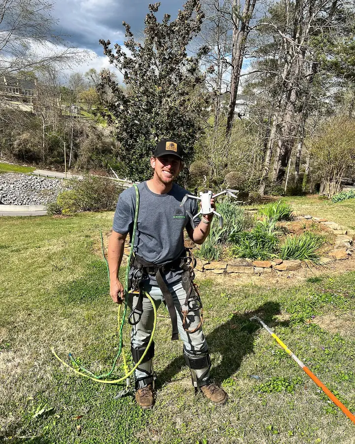 Jonny Brook in full climbing gear holding a recovered drone after a successful tree rescue