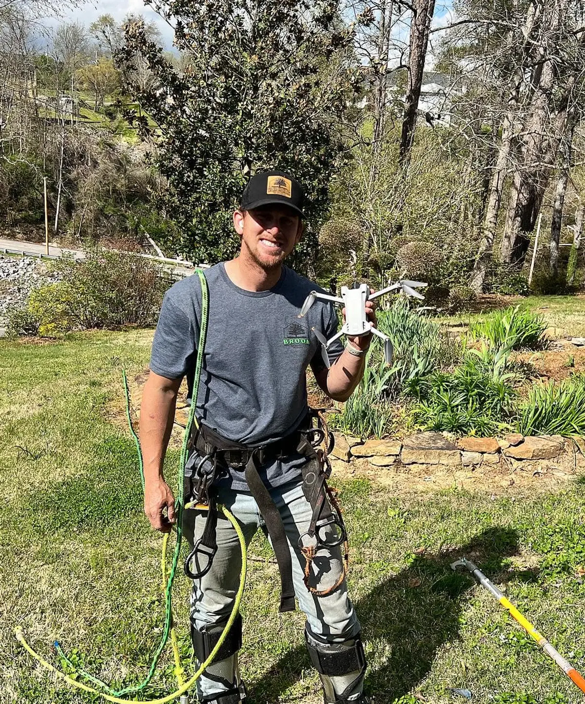 Jonny Brook in full climbing gear holding a recovered drone after a successful tree rescue