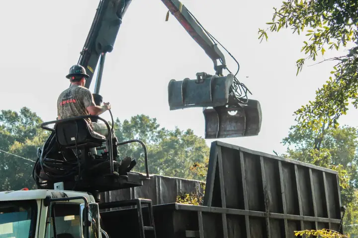 Grapple truck loading tree limbs and debris for haul-off